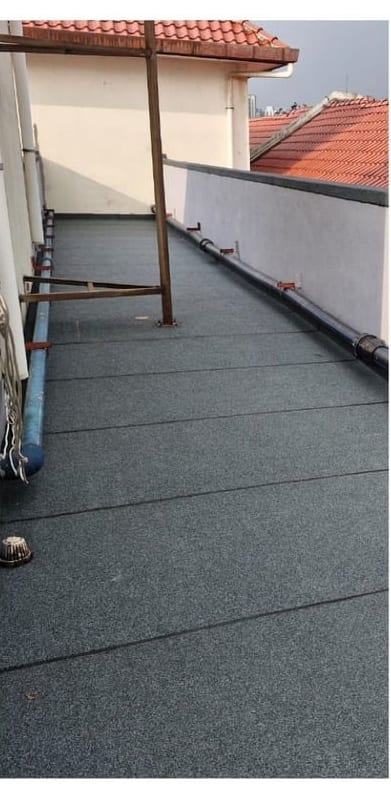 The walkway finished in dark membrane, pipes along one side.