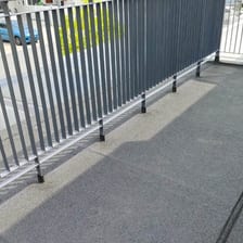 A finished dark membrane balcony beside a metal railing.