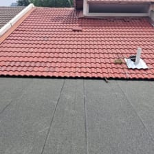 A dark membrane deck meeting a red clay tiled roof.